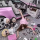 A woman laying on the ground with lipsticks and luxury bags around her.